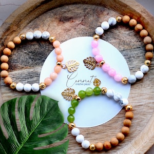 Könnte beinhalten: Drei Armbänder mit goldenen Blatt-Anhängern und verschiedenen farbigen Perlen. Die Armbänder bestehen aus weißen, rosa, grünen und braunen Perlen. Die Anhänger sind blattförmig. Die Armbänder liegen auf einer weißen Oberfläche mit dem Text "Cennet creative pieces".