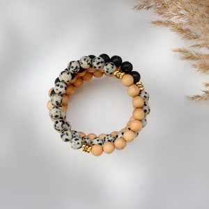 May include: A multi-strand bracelet with black, white, and brown beads. The bracelet is made of natural stones and wood.