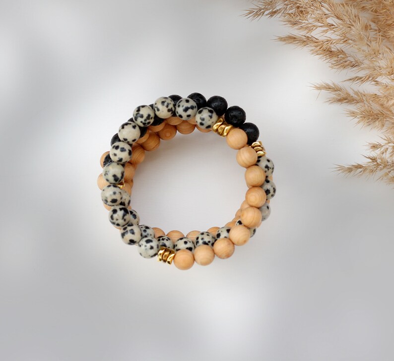 May include: A multi-strand bracelet with black, white, and brown beads. The bracelet is made of natural stones and wood.