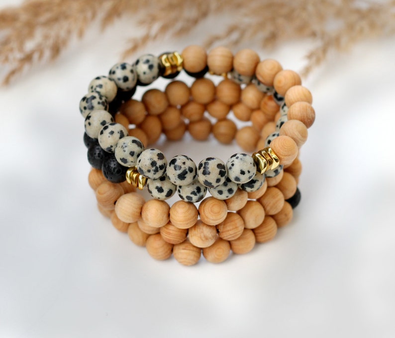 May include: A layered bracelet with black and white speckled beads, brown wooden beads, and gold spacers.