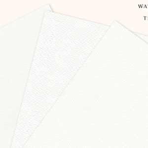 Peut inclure: Trois feuilles de papier aquarelle blanc avec une surface textur&eacute;e. Le papier est pli&eacute; en &eacute;ventail. Le texte "WATERCOLOR PAPER TEXTURES" est imprim&eacute; en noir en haut de l'image.