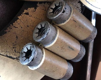 May include: Three brown metal cylinders with a star-shaped pattern around the top. The cylinders are attached to a larger object.
