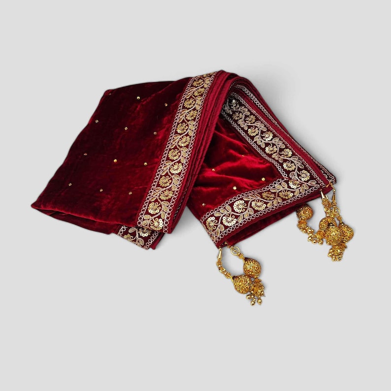 May include: A maroon velvet shawl with gold embroidery and tassels. The shawl has a floral design and is decorated with sequins.