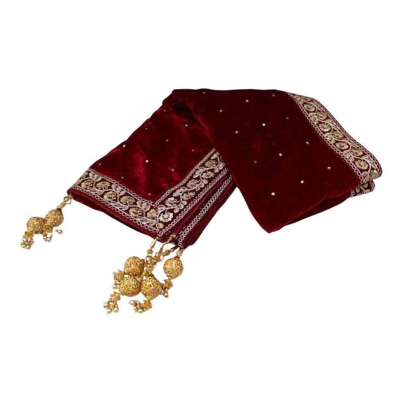 May include: A maroon velvet shawl with gold embroidery and tassels. The shawl has a delicate floral pattern and is adorned with small gold beads.