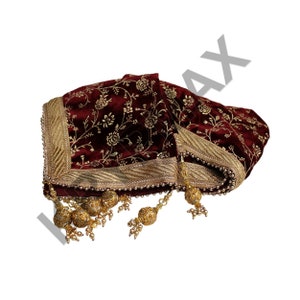 Op de afbeelding: Een vierkant van marroon fluweel met gouden borduurwerk en parelrand. De stof heeft een bloemenpatroon en de rand heeft gouden kwastjes.