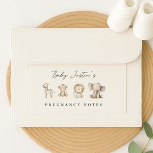 May include: A white folder with the text "Baby Justin's Pregnancy Notes" and a line of animal illustrations including a zebra, monkey, lion, and elephant.