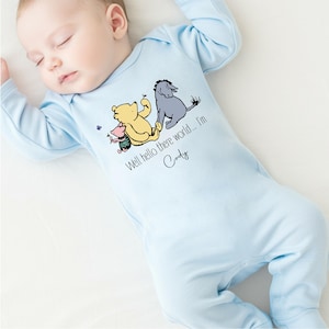 May include: A light blue baby onesie with a Winnie the Pooh, Piglet, and Eeyore graphic. The onesie has the text "Well hello there world... I'm Cody" printed on it.