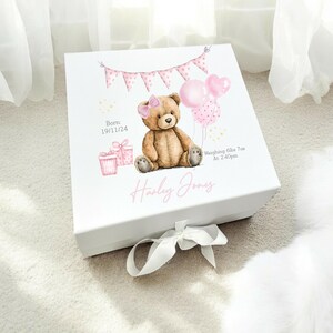 May include: White keepsake box with a watercolor illustration of a teddy bear, balloons, and gifts. The box has a pink bow and the name "Harley Jones" in pink script. Text includes birth details and weight.