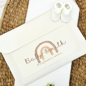 May include: A white pregnancy journal with a rainbow design and the text "Baby Smith Pregnancy notes".