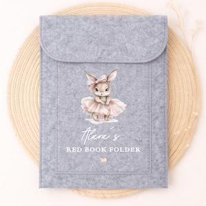 May include: A pale grey felt book folder with a flap closure. The front displays a watercolour illustration of a bunny in a pink tutu and bow. Text on the folder reads "Alara's RED BOOK FOLDER".