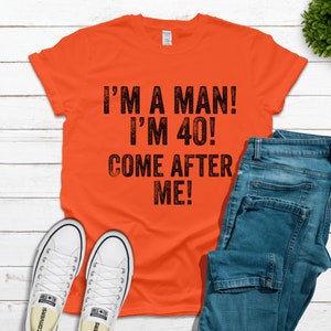 May include: Orange t-shirt with black text that reads "I'm a man! I'm 40! Come after me!"