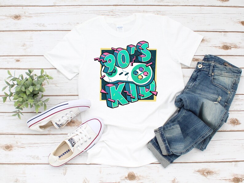 May include: White t-shirt with a graphic design of a retro video game controller and the text "90's Kid" in a colorful, 3D style.
