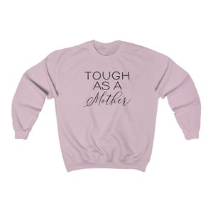 May include: A light pink sweatshirt with the text "TOUGH AS A MOTHER" printed in black.