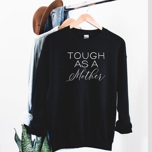 May include: Black sweatshirt with white text that reads "Tough as a Mother" on a black background.