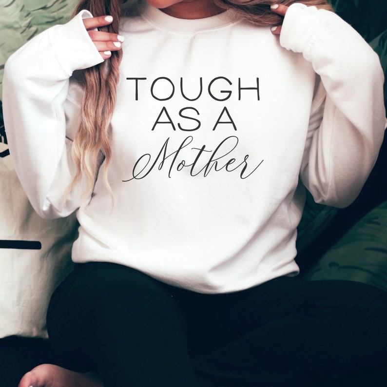 May include: White sweatshirt with the text "TOUGH AS A MOTHER" in black lettering.