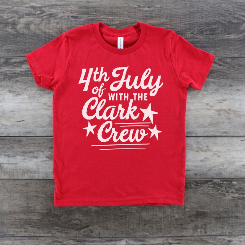 May include: Red t-shirt with white text that reads "4th of July with the Clark Crew" and stars.