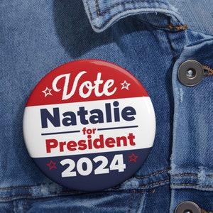May include: A red, white and blue button with the text "Vote Natalie for President 2024" on it.