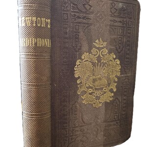 May include: A brown book with gold lettering on the spine that reads "NEWTON'S HARP-PHONIA". The front cover features a gold design with a crest and a bird.