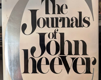 May include: The Journals of John Cheever book cover with a silver crescent moon design.
