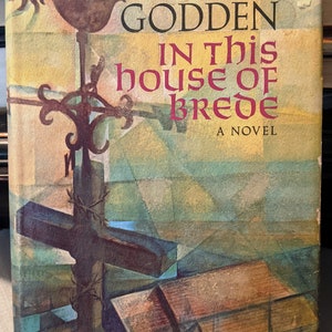 May include: A book cover with a watercolor illustration of a cross, a rooster weathervane, and a building. The title is "In This House of Brede" by Rumer Godden. A Novel.