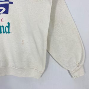Pu&ograve; includere: Felpa color crema con un design grafico blu e turchese. Il testo sulla felpa recita "nd". La felpa a maniche lunghe ha un girocollo e polsini a coste.