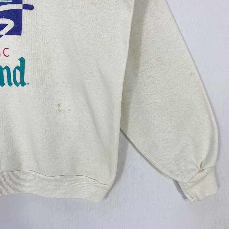 Pu&ograve; includere: Felpa color crema con un design grafico blu e turchese. Il testo sulla felpa recita "nd". La felpa a maniche lunghe ha un girocollo e polsini a coste.