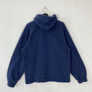 May include: A navy blue hoodie with a hood and long sleeves. The sweatshirt is hanging on a black hanger against a white background. The hoodie has a small logo on the chest.