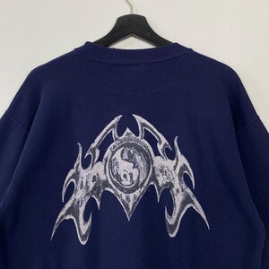 Puede incluir: Sudadera azul marino con un gran gr&aacute;fico blanco en la espalda. El gr&aacute;fico incluye el texto "T&C Surf Designs" y un emblema estilizado. La sudadera est&aacute; colgada de una percha negra.