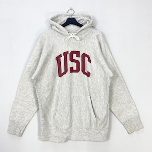 May include: A light gray hoodie with the letters "USC" in maroon across the chest. The hoodie has a drawstring hood, a front pocket, and ribbed cuffs and hem. The sweatshirt is made of a soft, comfortable material.
