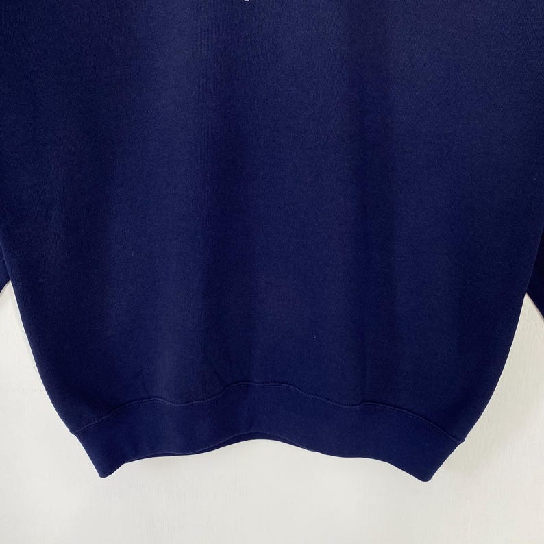 Puede incluir: Una sudadera azul marino con cuello redondo y mangas largas. La sudadera tiene dobladillo y pu&ntilde;os acanalados. La prenda es de color liso y parece nueva. La tela es suave.