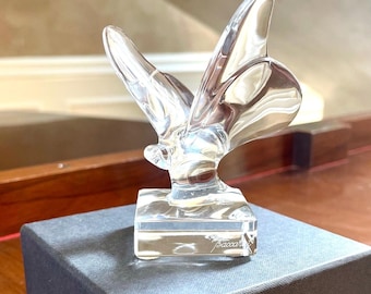 Könnte beinhalten: Eine durchsichtige Kristall-Schmetterlingsfigur auf einem quadratischen Sockel. Der Sockel ist mit dem Wort "Baccarat" graviert. Die Figur steht auf einer grauen Box.