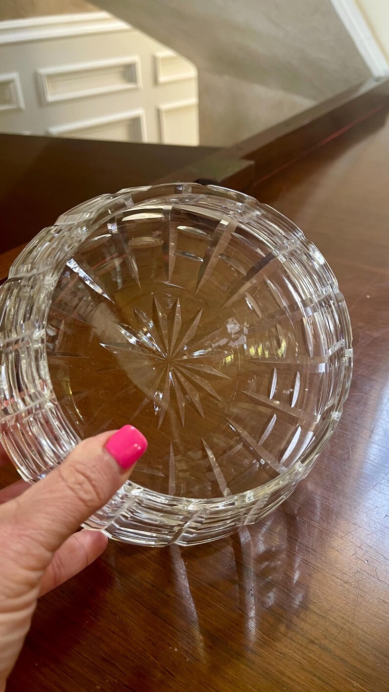 K&ouml;nnte beinhalten: Eine klare, geschliffene Glasschale mit einem Sternmuster in der Mitte. Die Schale hat eine runde Form mit einer strukturierten, gerippten Au&szlig;enseite. Die Schale steht auf einer dunkelbraunen Holzoberfl&auml;che.