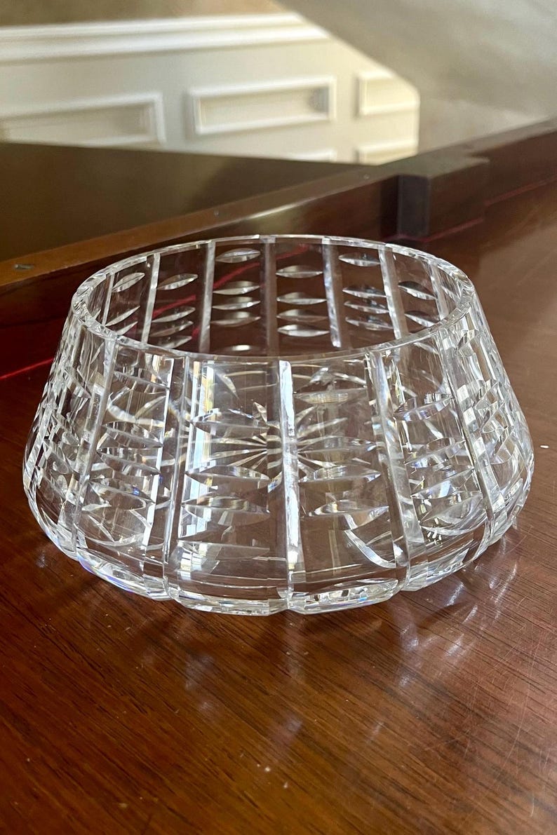 K&ouml;nnte beinhalten: Eine klare, geschliffene Kristallschale mit einer breiten, ausgestellten Form. Die Schale weist komplizierte geometrische Muster und Sternmuster auf, die das Licht reflektieren. Die Schale ist wahrscheinlich aus Bleikristall und f&uuml;r dekorative Zwecke geeignet.