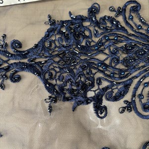 May include: Navy blue beaded lace fabric with a delicate floral pattern. The lace is on a sheer mesh background.