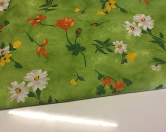 May include: Green fabric with a floral print featuring white daisies, orange poppies, and yellow flowers.