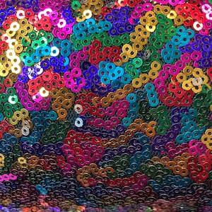 Könnte beinhalten: Nahaufnahme eines Stoffes, der mit schillernden Pailletten in verschiedenen Farben bedeckt ist, darunter Blau, Grün, Rot, Pink, Gold und Lila.