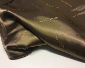 May include: Close-up of a brown satin fabric with the text "Bruce & Borough" embossed in gold.