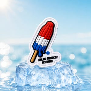 Peut inclure: Un charm décoratif en forme de glace à l'eau rouge, blanche et bleue avec un bâtonnet beige. Le motif présente une petite icône de flocon bleu et le texte noir COOLING PROTOCOL: ACTIVATED, le tout entouré d'une épaisse bordure blanche.