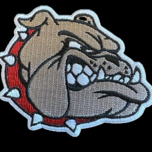 May include: Embroidered patch of a gray bulldog with a red collar and white spikes. The bulldog has a fierce expression with bared teeth.