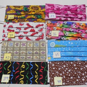 May include: Ten fabric face masks with different patterns, including sunflowers, cars, dogs, stars, and confetti. Each mask has a number written on it, ranging from 33 to 40.