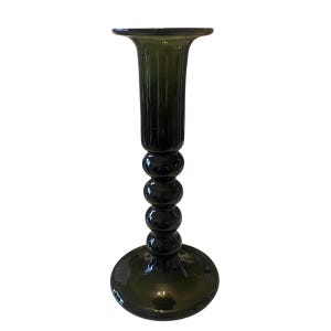 May include: Dark green glass candlestick holder with a flared top and a series of rounded spheres along the stem. The base is a wide, circular shape. The candlestick holder is a decorative item for a table or shelf.