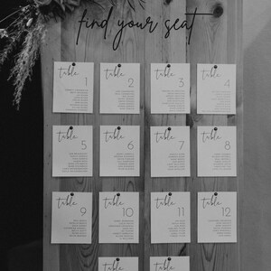 May include: A wooden seating chart with white cards listing table numbers and guest names. The sign reads "find your seat".
