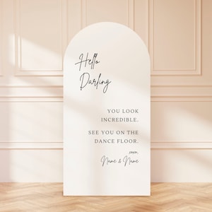 May include: White arch-shaped sign with the text "Hello Darling" in black cursive script. The sign also includes the text "You look incredible. See you on the dance floor. xoxo, Name & Name" in black text.