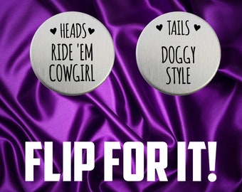 May include: Two silver round tokens with black text on a purple satin background. The text on the tokens reads "Heads Ride 'Em Cowgirl" and "Tails Doggy Style". The text "Flip For It!" is printed in white below the tokens.