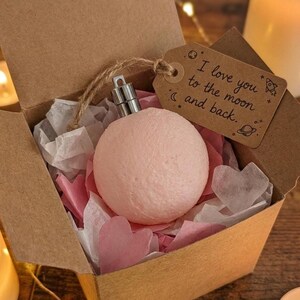Pink moon lamp ornament in an eco-friendly gift box with heart-shaped tissue paper, space-themed gift tag that reads ‘I love you to the moon and back.’ Shot in warm, romantic light.
