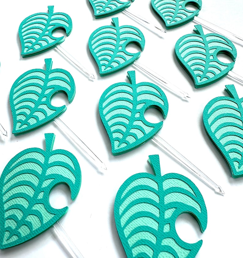 May include: A collection of teal leaf-shaped party picks. Each pick features a detailed leaf design with a clear plastic stem. The leaves are a vibrant teal color, and the design is reminiscent of a popular video game.
