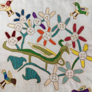 May include: Embroidered textile featuring colorful birds and stylized flowers in shades of red, blue, green, yellow, and purple. The design is set against a cream-colored background, showcasing a folk art style.