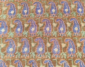 May include: A close-up of a patterned rug with a repeating design of blue and white flowers on a brown background.