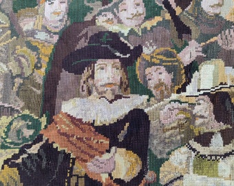 May include: A close-up of a needlepoint tapestry depicting a group of people in period clothing. The tapestry is made with colorful yarn and features a variety of textures. The central figure is a man with a beard and a black hat.