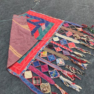 May include: A colorful patchwork quilt with a geometric design and fringe. The quilt is made of various fabrics in shades of red, blue, green, and brown.